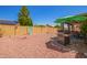 Beautiful backyard with a covered patio, lush greenery, and low-maintenance gravel landscaping at 9234 W Sierra Pinta Dr, Peoria, AZ 85382