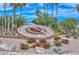 Community Clock encircled with vibrant flowers and greenery, set against a backdrop of mature trees and a clear blue sky at 9234 W Sierra Pinta Dr, Peoria, AZ 85382