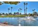 Scenic golf course view with a sparkling pond featuring a fountain, lush green grass, and swaying palm trees under blue skies at 9234 W Sierra Pinta Dr, Peoria, AZ 85382