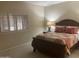 Bedroom featuring a wood bed frame with red pillows, a bedside table, and plantation shutters at 11360 E Keats Ave # 75, Mesa, AZ 85209