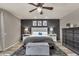 A well-lit main bedroom featuring a tufted headboard, soft gray walls, and a dark wood dresser at 13323 W Rancho Dr, Litchfield Park, AZ 85340