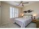 Well-lit bedroom with neutral decor, featuring a comfortable bed, modern light fixture and shuttered windows at 15134 W Waterford Dr, Surprise, AZ 85374