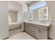 Bathroom featuring an en suite bath, dual vanity, modern cabinetry and brushed gold hardware at 15766 W Grand Point Ln, Surprise, AZ 85374