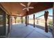 Relaxing covered patio featuring a ceiling fan and decorative curtains overlooking a landscaped backyard at 17050 W Manchester Dr, Surprise, AZ 85374