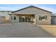 Home's backyard featuring a covered patio, neutral gravel, and block fence with shade on the right side at 19231 W Missouri Ave, Litchfield Park, AZ 85340