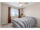 Bedroom with neutral walls and carpet, features a ceiling fan, window, and dresser at 19933 N Emmerson Dr, Maricopa, AZ 85138