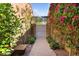 Charming courtyard entrance with brick pathway, vibrant bougainvillea, and secure gate, creating a private oasis at 21109 W Sunrise Ln, Buckeye, AZ 85396