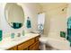 Bright bathroom featuring a vanity with wood cabinets, oval mirror, bathtub with shower, and coordinated turquoise accents at 22626 W Gibson Ln, Buckeye, AZ 85326