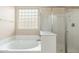 Bathroom featuring a tub, a glass-enclosed shower, and a window for natural light at 2329 E Ebony Dr, Chandler, AZ 85286