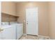 Laundry room featuring a side-by-side washer and dryer with overhead shelf storage and a door at 2329 E Ebony Dr, Chandler, AZ 85286