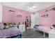Bright pink bedroom with two beds, ceiling fan, and tiled floors provides a cheerful and comfortable space at 23848 W Grove St, Buckeye, AZ 85326