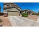A charming house features desert-style landscaping, an attached garage and a concrete driveway at 23848 W Grove St, Buckeye, AZ 85326