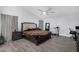 Main bedroom features wood-look tile flooring, a ceiling fan, and a tufted king-size bed at 23848 W Grove St, Buckeye, AZ 85326