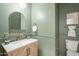Stylish powder room with green walls, brass fixtures, and a framed mirror at 25925 N 53Rd Dr, Phoenix, AZ 85083