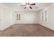 A spacious bedroom features neutral carpet, a ceiling fan, and shuttered windows, creating a bright, airy atmosphere at 28967 N 124Th Ave, Peoria, AZ 85383