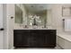 Well-lit bathroom features double sinks, dark cabinets, modern fixtures, and decorative flowers at 296 N Jesse St, Chandler, AZ 85225