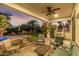 Covered patio with comfortable lounge seating overlooking the landscaped backyard with a pool and desert sunset at 2977 E County Down Dr, Chandler, AZ 85249