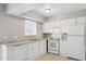 Bright kitchen featuring a window, a set of white appliances, light countertops, and white cabinetry at 3605 W Bethany Home Rd # 7, Phoenix, AZ 85019