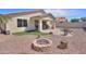 Wide shot of the backyard with artificial turf, firepit, desert landscaping, and covered patio at 46141 W Amsterdam Rd, Maricopa, AZ 85139