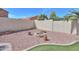 Landscaped backyard featuring a brick fire pit, desert landscaping and palm trees at 46141 W Amsterdam Rd, Maricopa, AZ 85139