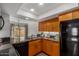 A well-lit kitchen with wood cabinets, granite countertops, modern appliances, and a black refrigerator at 5221 E Tunder Cir, Phoenix, AZ 85044