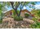 Spacious backyard featuring a large tree, desert landscaping, and a covered patio at 7500 E Pontebella Dr, Scottsdale, AZ 85266