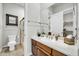 The bright bathroom features a wood vanity with a sink, a shower with glass door, and access to the walk-in closet at 7500 E Pontebella Dr, Scottsdale, AZ 85266