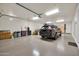 Spacious garage featuring epoxy floors, storage cabinets, and a modern black SUV parked inside at 7500 E Pontebella Dr, Scottsdale, AZ 85266