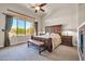 Spacious main bedroom featuring a ceiling fan, large window, and a stately wooden bed frame with an upholstered bench at 7500 E Pontebella Dr, Scottsdale, AZ 85266