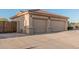 Close up of a three car garage with stone detail and brown doors at 8220 W Mariposa Grande Ln, Peoria, AZ 85383