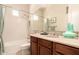 Bathroom features a vanity with warm wood cabinets, white tiled shower and tub combo with a beige countertop at 9747 S 182Nd Dr, Goodyear, AZ 85338