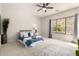 This bright bedroom features a large window, ceiling fan, neutral carpet, and a blue accented bed at 9747 S 182Nd Dr, Goodyear, AZ 85338