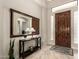 Inviting foyer featuring a wooden door, travertine floors, a large mirror and stylish decor at 9747 S 182Nd Dr, Goodyear, AZ 85338