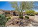 Beautiful desert home with lush landscaping, including a mature tree providing shade and curb appeal at 9747 S 182Nd Dr, Goodyear, AZ 85338