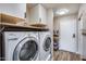 Functional laundry room with white washer and dryer, overhead cabinets, and convenient shelving at 18642 N 13Th Ave, Phoenix, AZ 85027