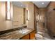 Bathroom featuring warm tones, marble countertops, glass enclosed shower, and modern lighting fixtures at 43105 N 102Nd St, Scottsdale, AZ 85262
