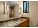 Bathroom featuring warm tones, marble countertops, glass enclosed shower, and modern lighting fixtures at 43105 N 102Nd St, Scottsdale, AZ 85262