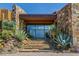 Beautiful stone home entrance with mature desert landscaping and stone walkway steps to the modern front door at 43105 N 102Nd St, Scottsdale, AZ 85262