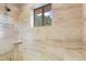 Bright bathroom featuring a stone-tiled shower with a shower head and shower caddy, and a window to the exterior at 6621 N Arizona Biltmore Cir, Phoenix, AZ 85016