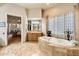 Luxurious bathroom featuring a soaking tub, marble tile, and a vanity with dual sinks at 6621 N Arizona Biltmore Cir, Phoenix, AZ 85016