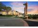 Elegant home with palm trees, manicured lawn, and a circular brick driveway at dusk at 6621 N Arizona Biltmore Cir, Phoenix, AZ 85016