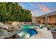 A captivating pool and spa area, with rock waterfall feature and lush greenery at 6621 N Arizona Biltmore Cir, Phoenix, AZ 85016