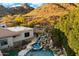An aerial view of a pool, waterfall, and backyard with mature desert vegetation at 6621 N Arizona Biltmore Cir, Phoenix, AZ 85016