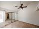 Bright bedroom features mirrored closet, ceiling fan, and neutral carpet at 10 E Betty Elyse Ln, Phoenix, AZ 85022