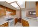 Well-lit kitchen with white appliances, tiled floors, and light wood cabinets at 10 E Betty Elyse Ln, Phoenix, AZ 85022