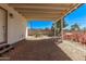 A cozy covered patio with a gravel floor and a view of the blooming garden and blue sky at 115 S Stardust Ln, Apache Junction, AZ 85120