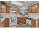 Charming kitchen featuring wood cabinetry, white appliances, and tile flooring at 14123 W Yosemite Dr, Sun City West, AZ 85375