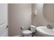Neutral toned half-bathroom featuring a modern sink, toilet, and artistic print on the wall at 14770 W Voltaire St, Surprise, AZ 85379