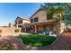 Back exterior view with covered patio, outdoor furniture, synthetic grass, and gravel at 15432 W Yucatan Dr, Surprise, AZ 85379