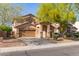 Attractive home with a two-car garage and covered entrance, complemented by mature desert trees at 15432 W Yucatan Dr, Surprise, AZ 85379